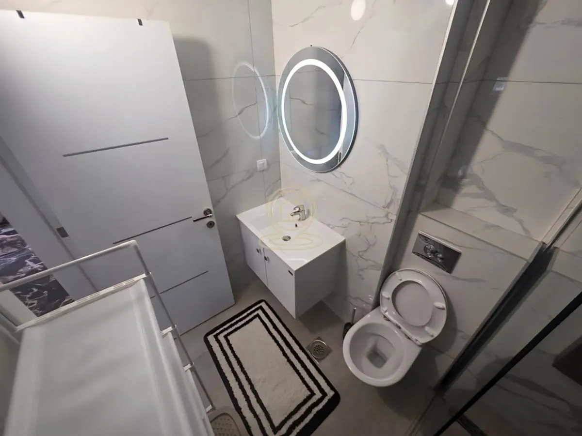 Savremeno opremljeno kupatilo sa umivaonikom, ogledalom i WC šoljom.