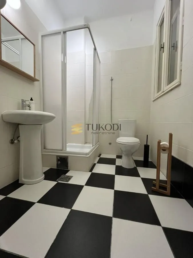 Bathroom with a shower cabin and black and white ceramic floor tiles.