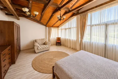 Spacious bedroom with wooden ceiling beams, a double bed and large windows. - image 2
