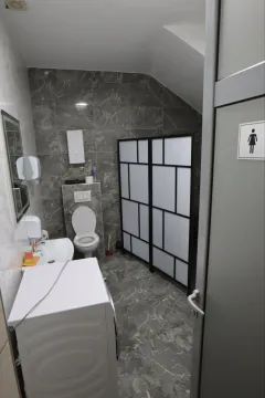 Modernly equipped bathroom with a shower cabin, sink, and toilet. - image 6