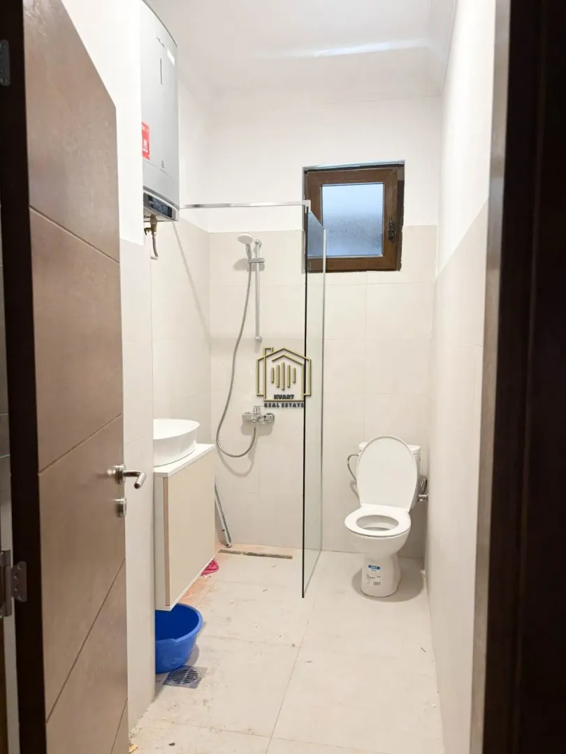 Smaller bathroom with a shower cabin, washbasin, and toilet.