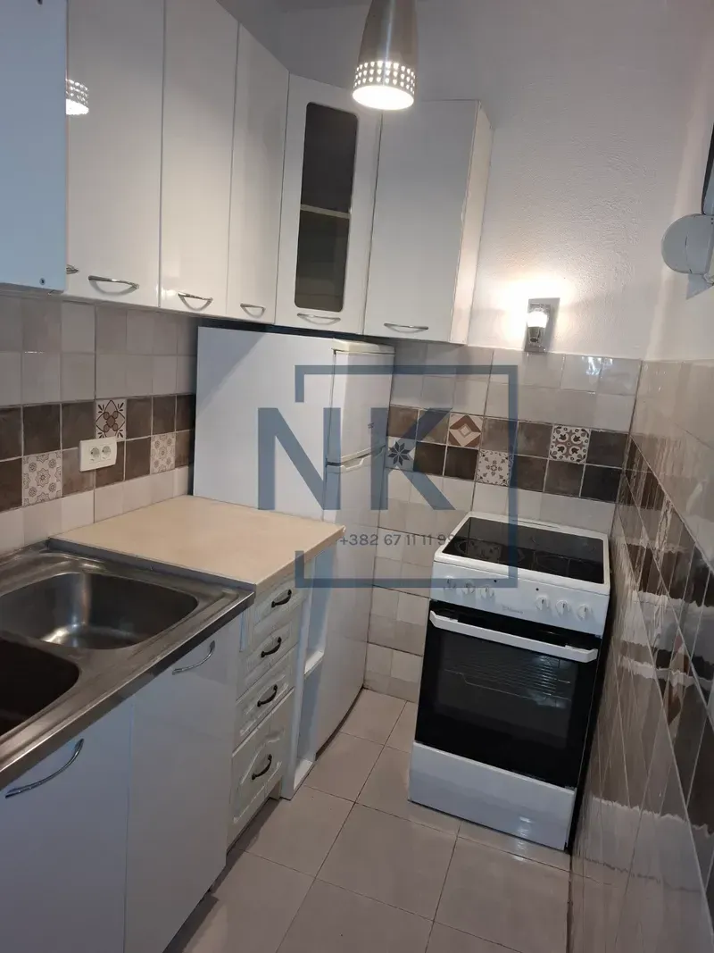 Small kitchen with white cabinets, refrigerator, and stove.
