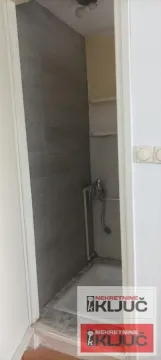 Manje kupatilo sa tuš kabinom obloženom tamnim pločicama. - image 14