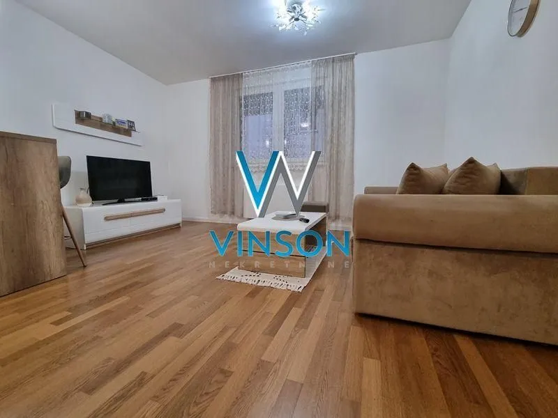 Nameštena dnevna soba sa garniturom i televizorom.