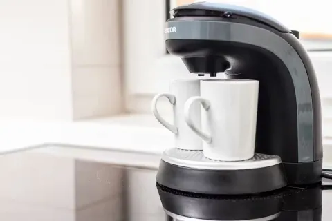 Close-up of a coffee maker with two white cups on a kitchen surface. - image 20