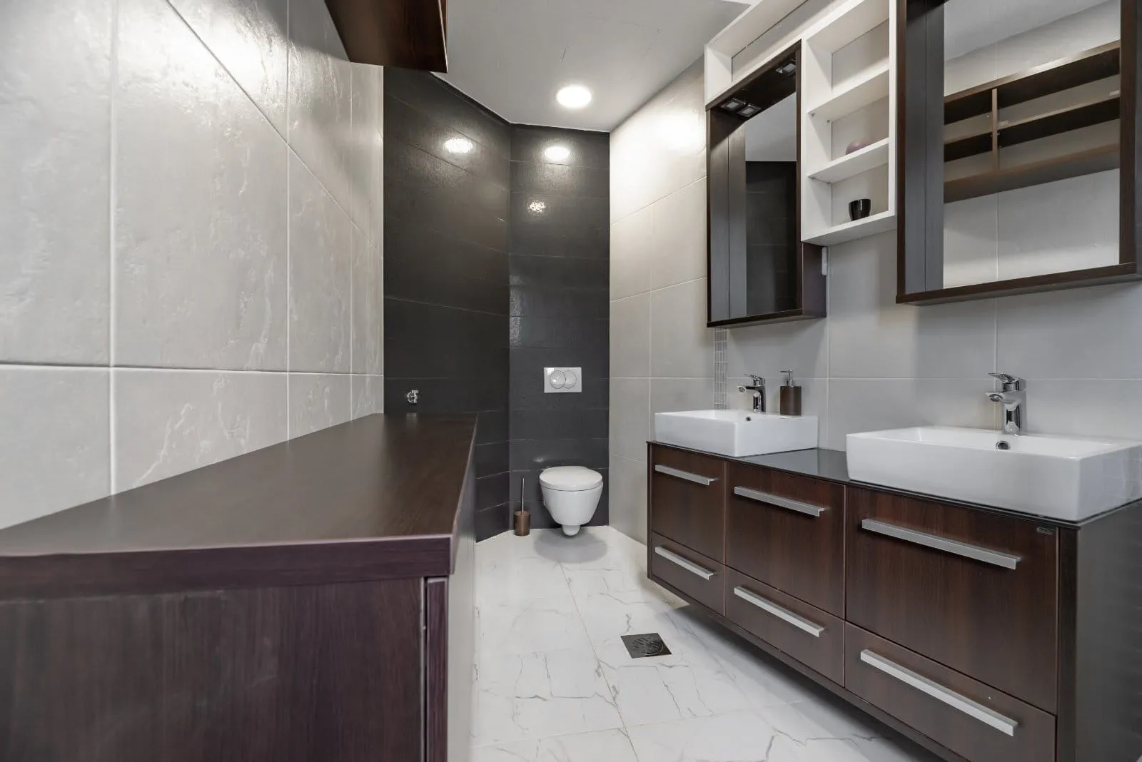Modern bathroom with two sinks, dark vanity units, and a toilet.