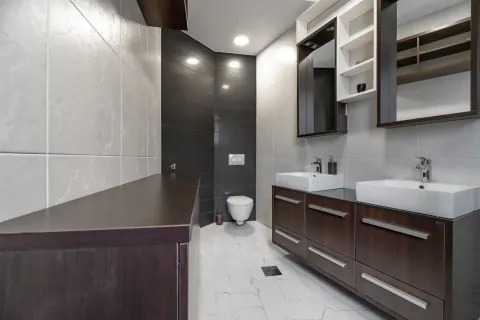 Modern bathroom with two sinks, dark vanity units, and a toilet. - image 18