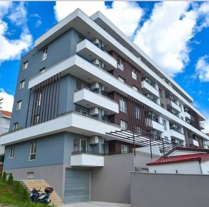 Exterior of a modern apartment building with balconies and a garage.