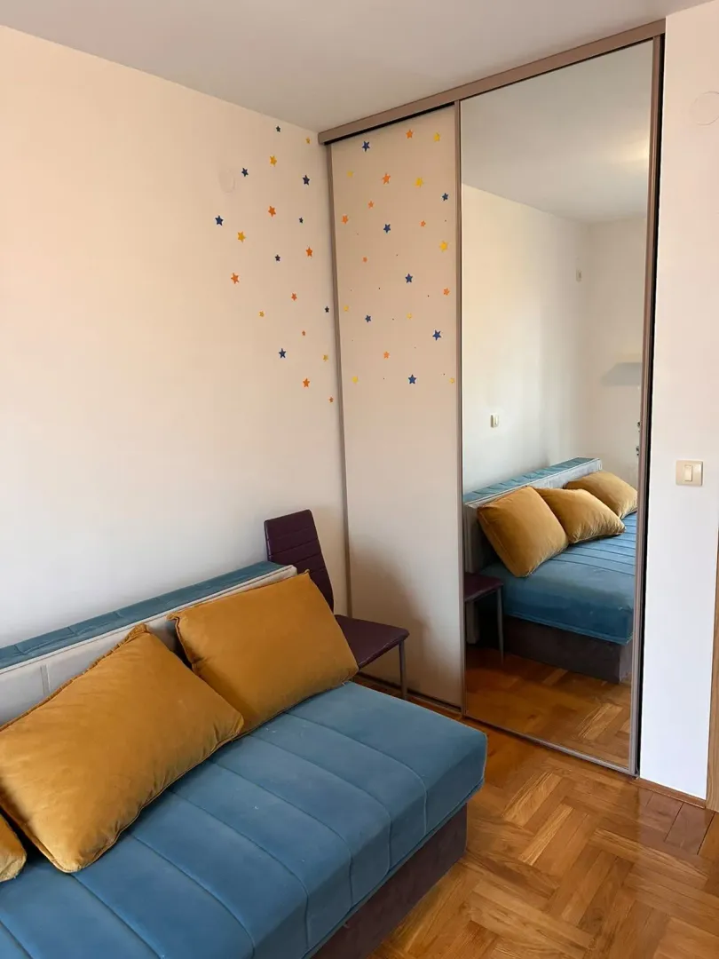 Children's bedroom with a bed, mirrored wardrobe, and wall decorations.