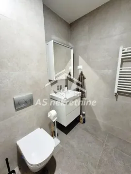 Modern bathroom with a washbasin, mirror, and toilet, tiled in grey. - image 11