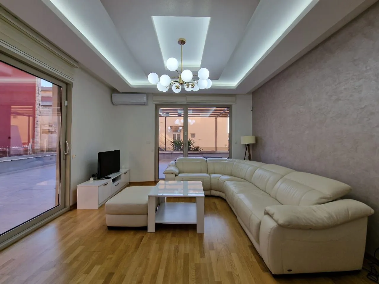Spacious living room with a large white sectional sofa, coffee table, and TV.