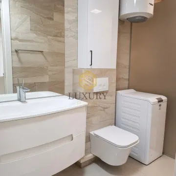 Modern bathroom equipped with a washbasin, toilet, and washing machine. - image 9
