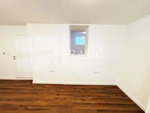Empty room with white walls and dark laminate flooring. - image 2