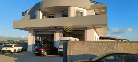 Exterior of a multi-story commercial and residential building with a yard and parked vehicles. - image 3