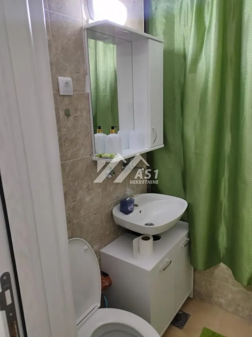 Manje kupatilo sa umivaonikom, ogledalom, ormarićem i toaletnom šoljom.