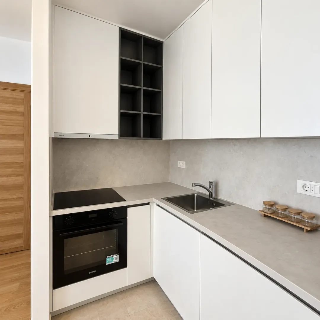 Modern white kitchen with built-in oven, hob, and sink.