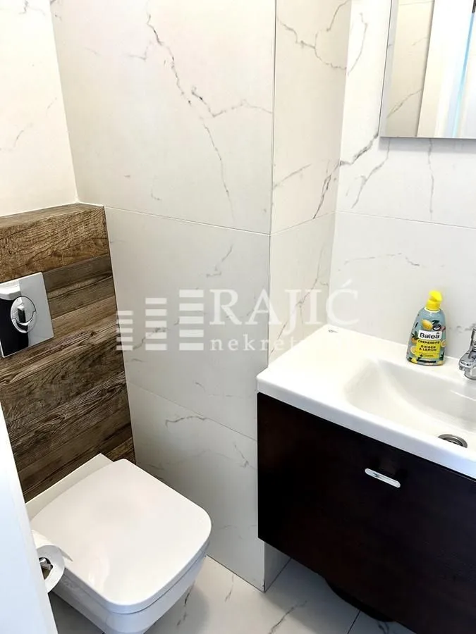 Modern bathroom with white marble tiles and built-in fixtures.