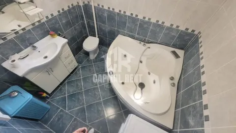 Kupatilo opremljeno umivaonikom, ugaonom kadom i toaletom sa pločicama u plavim tonovima. - image 9