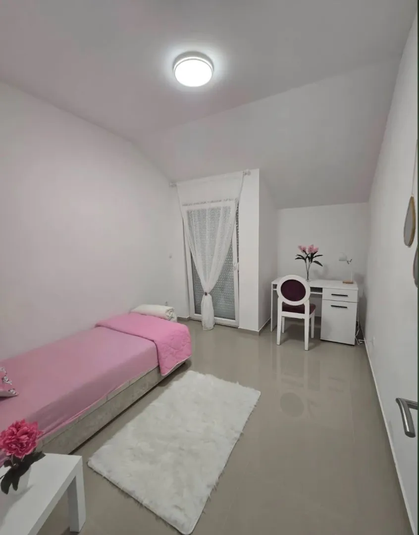 Tidy bedroom with a bed, desk, and white walls.