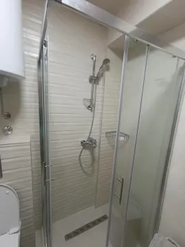 Kupatilo sa tuš kabinom i keramičkim pločicama u svijetlim tonovima. - image 16