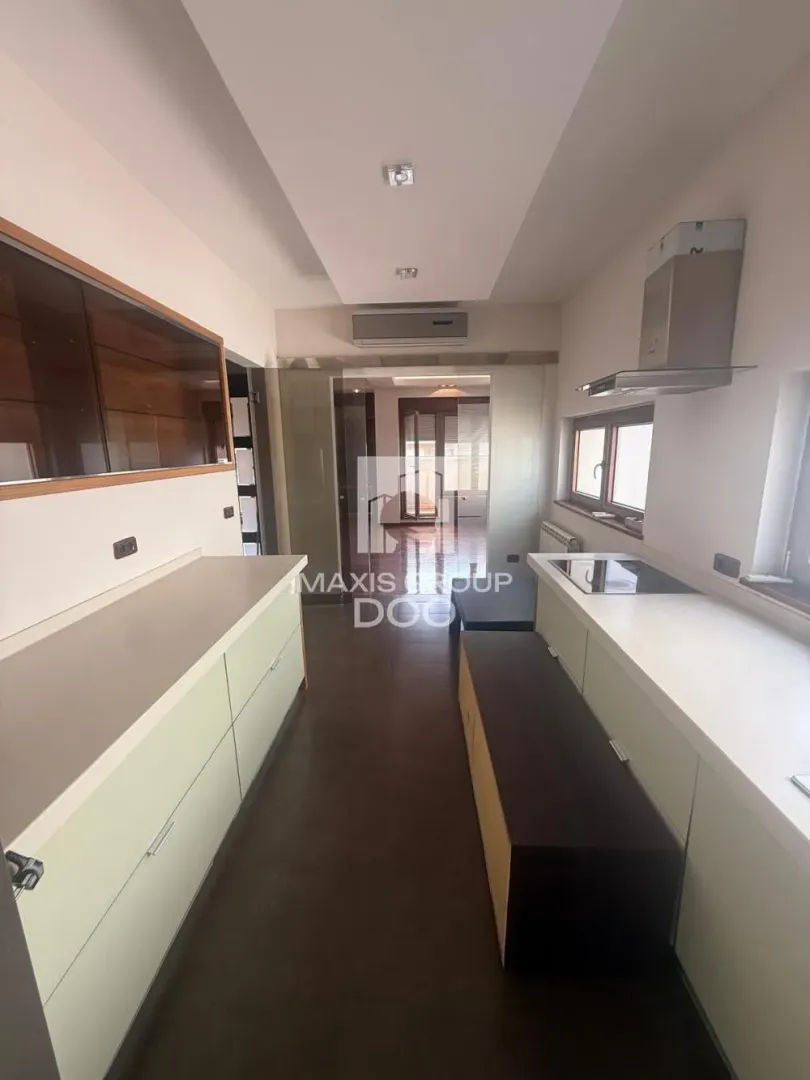Narrow kitchen with white cabinetry and built-in appliances.
