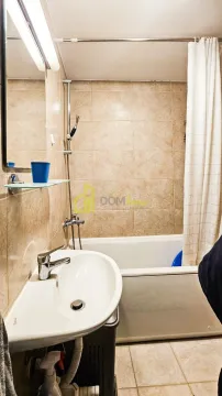 Small bathroom with a washbasin, mirror, and a bathtub with a curtain. - image 2