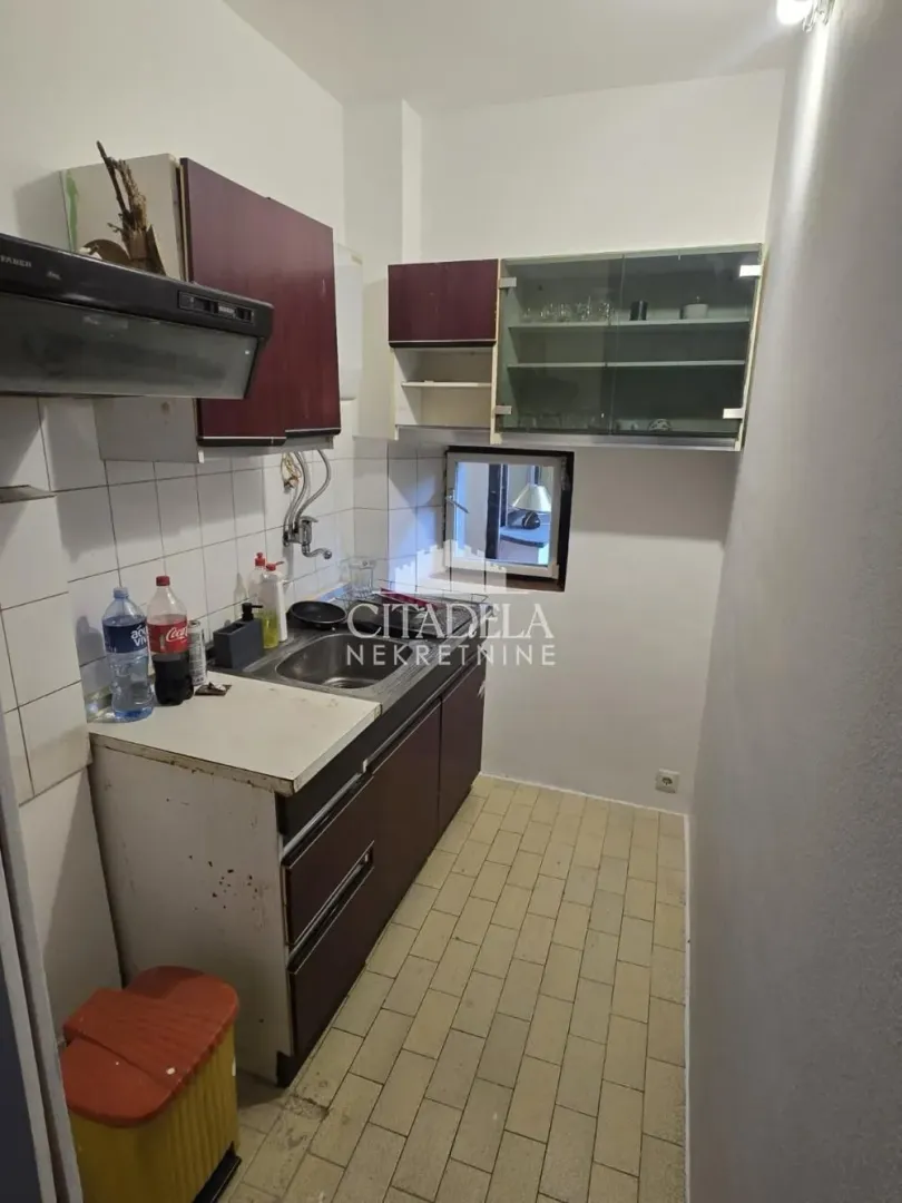 Manja kuhinja sa sudoperom, elementima i radnom površinom.