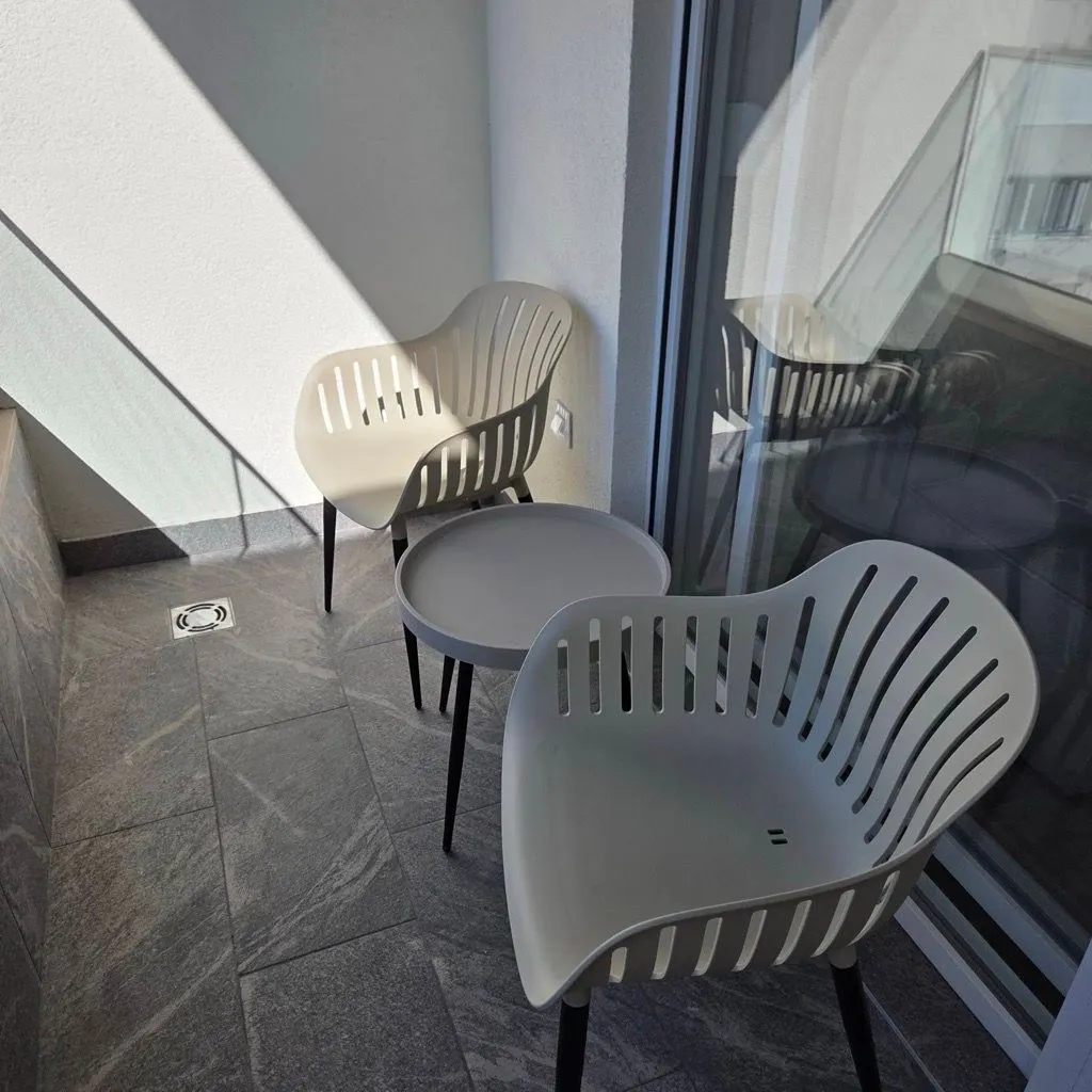 Small balcony furnished with two modern chairs and a small table.