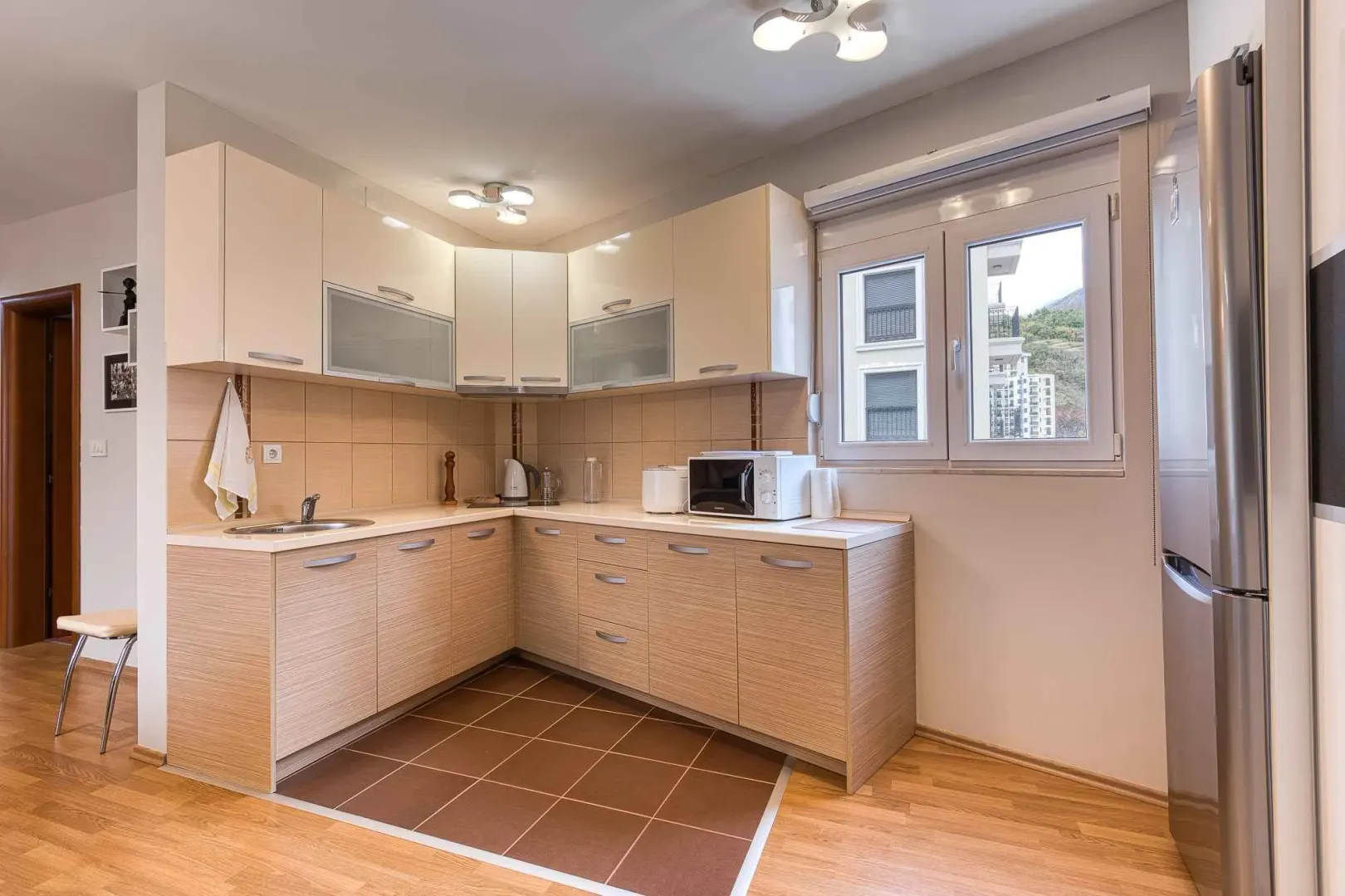 L-shaped kitchen with light cabinetry and a sink by the window.
