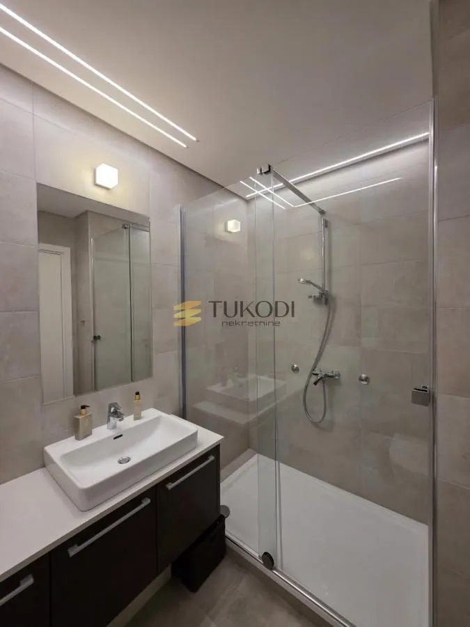 Modern bathroom with a walk-in shower, washbasin, and mirror.
