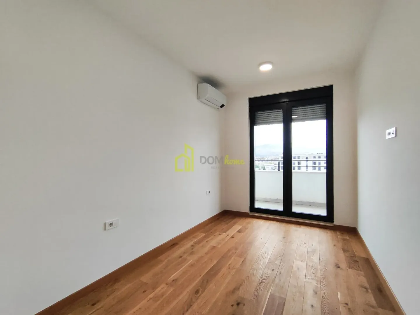 Empty bright room with wooden flooring and access to a terrace.