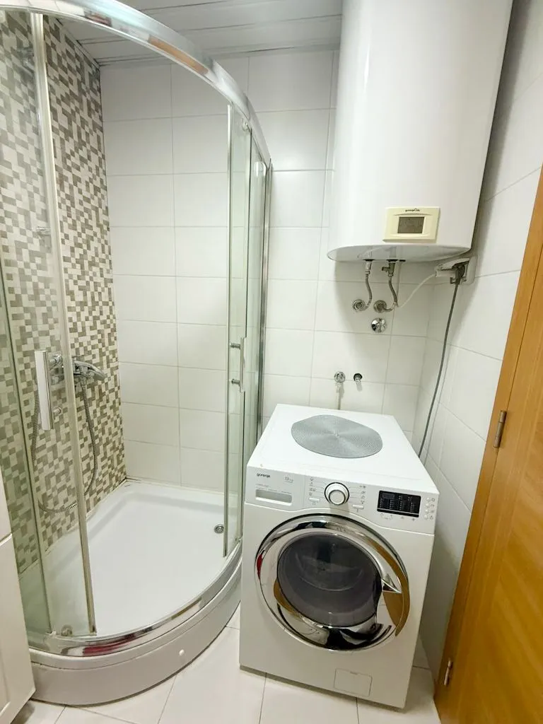 Small bathroom with a shower cabin, washing machine, and water heater.
