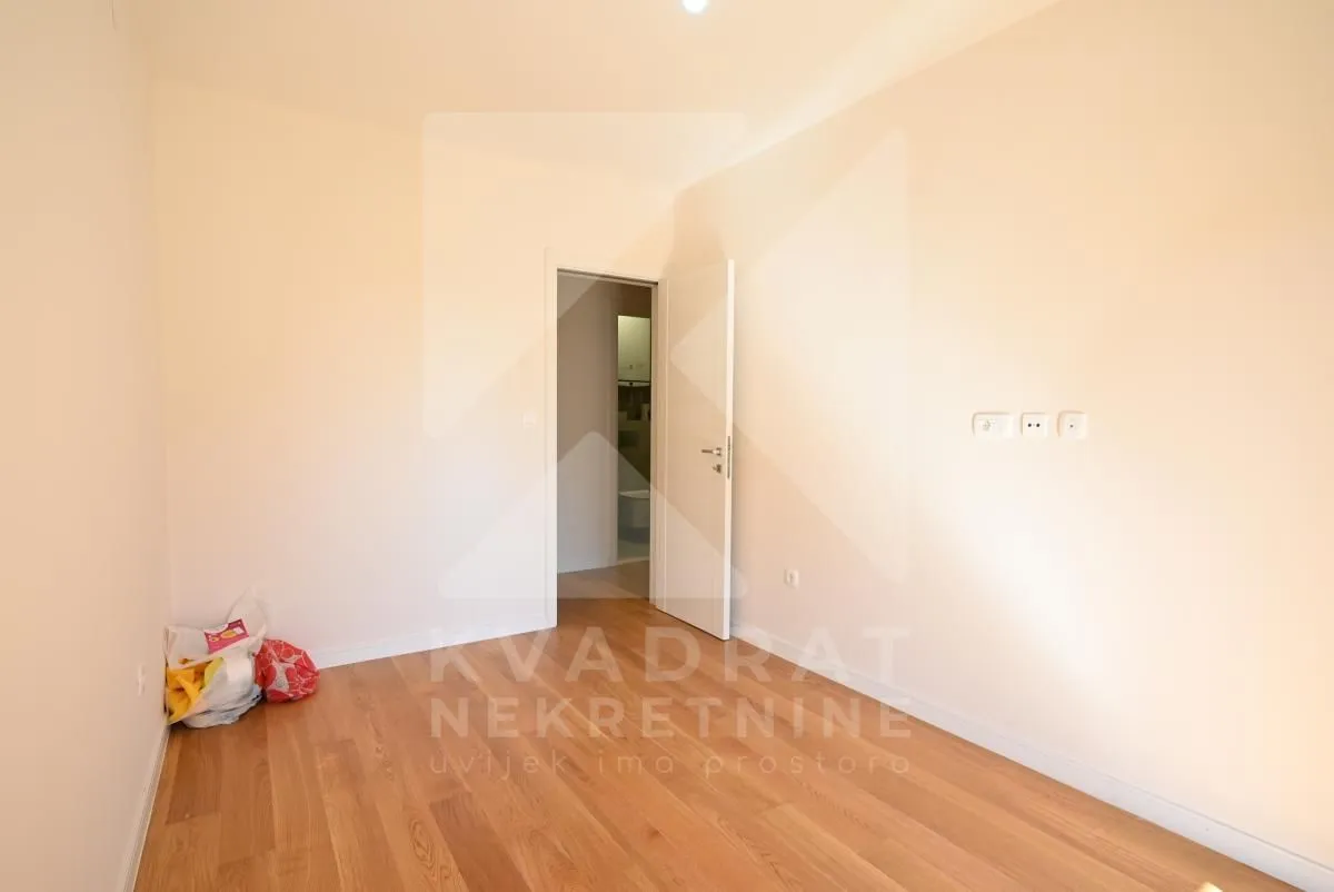 Empty room with wooden flooring and an open door.
