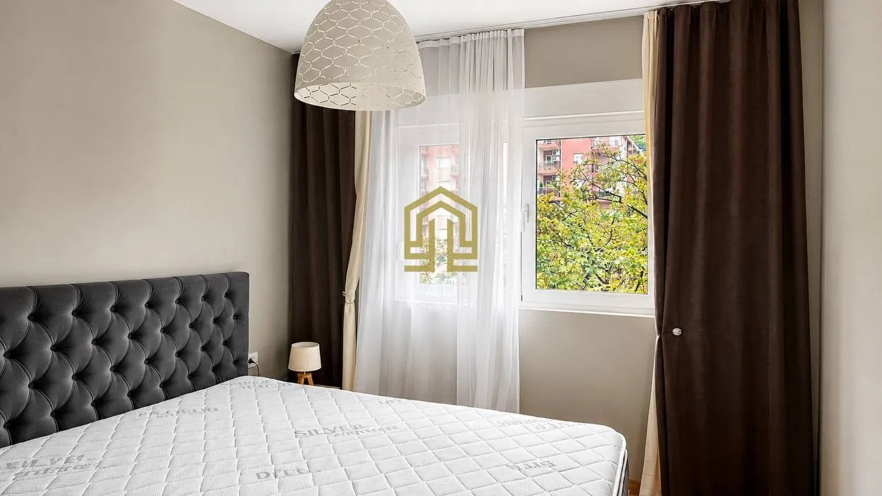 Bright bedroom featuring a grey tufted headboard and a large window.
