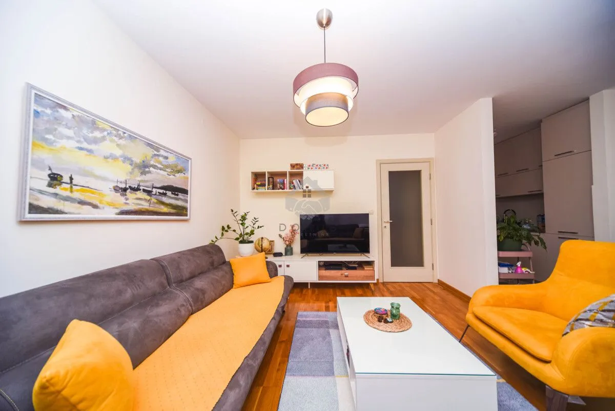 Living room with sofa, armchair, TV, and an art painting on the wall.