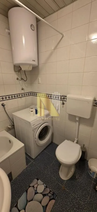 Manje kupatilo sa kadom, veš mašinom i bojlerom na zidu.