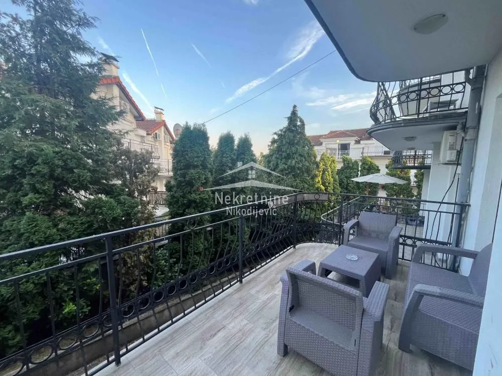 Furnished balcony with seating set and view of greenery.