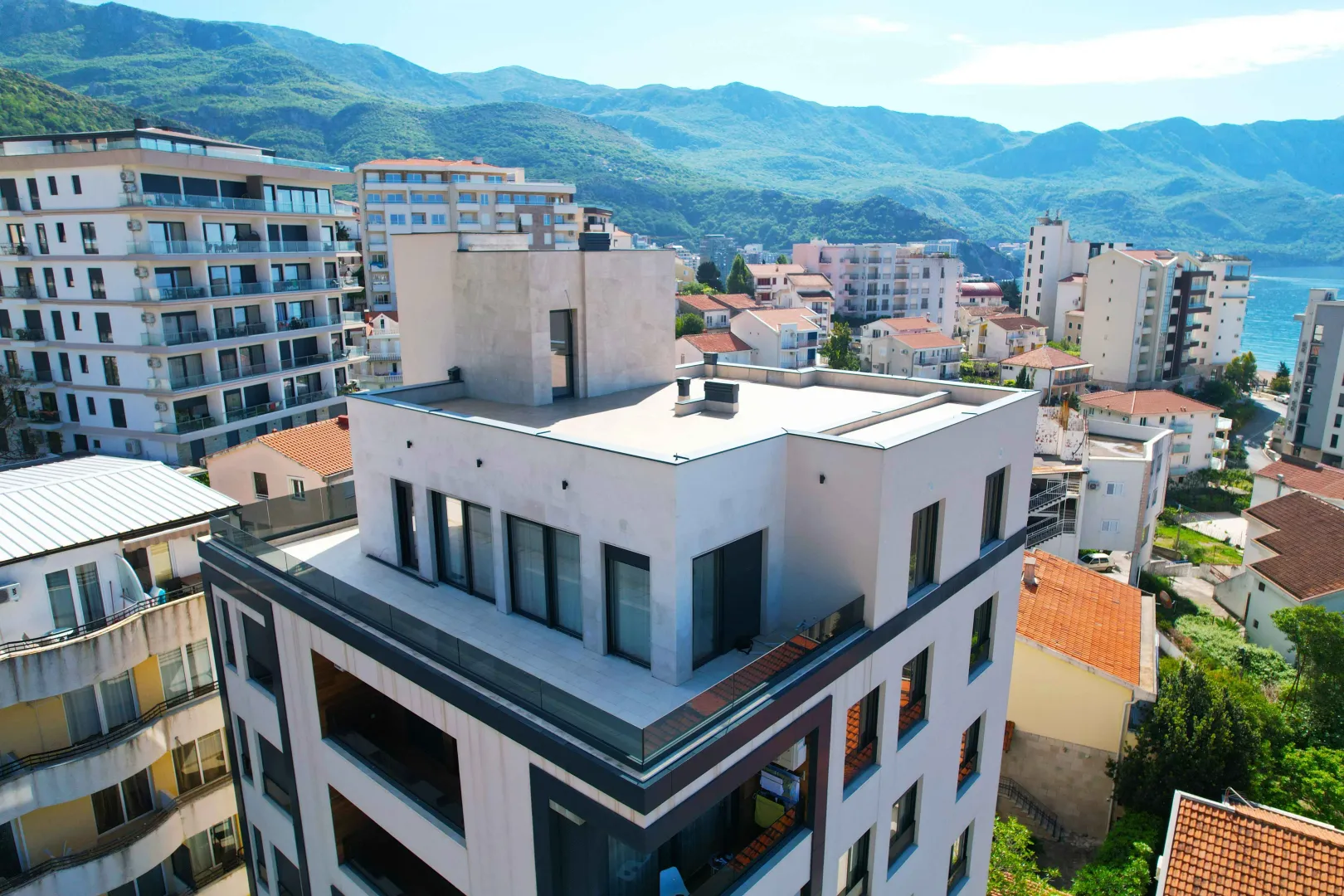 Moderna stambena zgrada sa prostranom krovnom terasom i pogledom na planine.