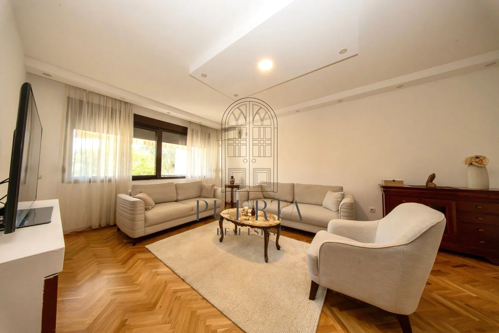 Spacious and bright living room with seating set and parquet flooring.