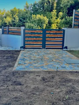 Yard with a modern gate and paved driveway. - image 10