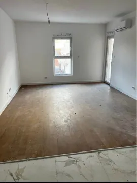 Empty room with wooden flooring, white walls, window, and air conditioning unit. - image 2