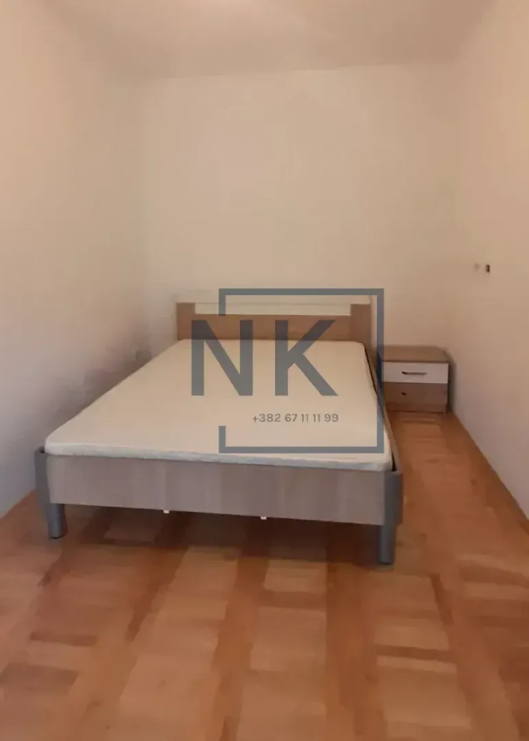 Spavaća soba sa bračnim krevetom i noćnim stočićem.
