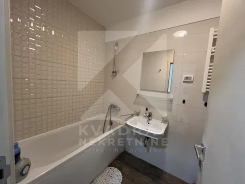 Bathroom equipped with a bathtub, washbasin, and mirror with neutral-toned tiles. - image 7