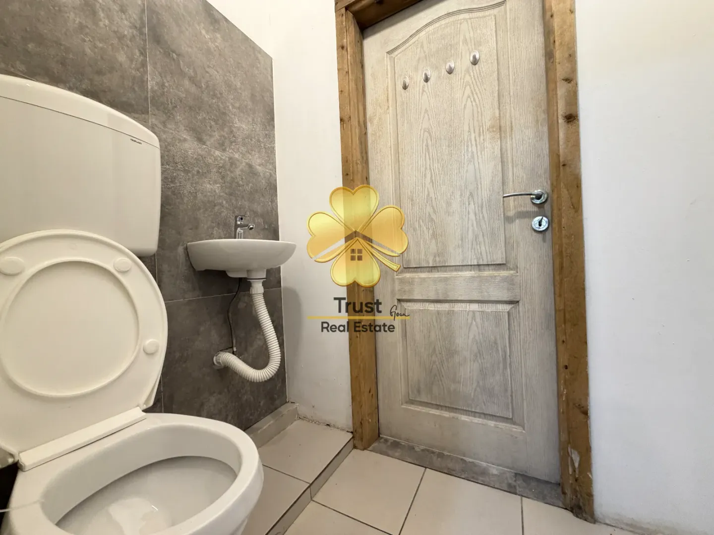 Small bathroom with a toilet, washbasin, and wooden door.