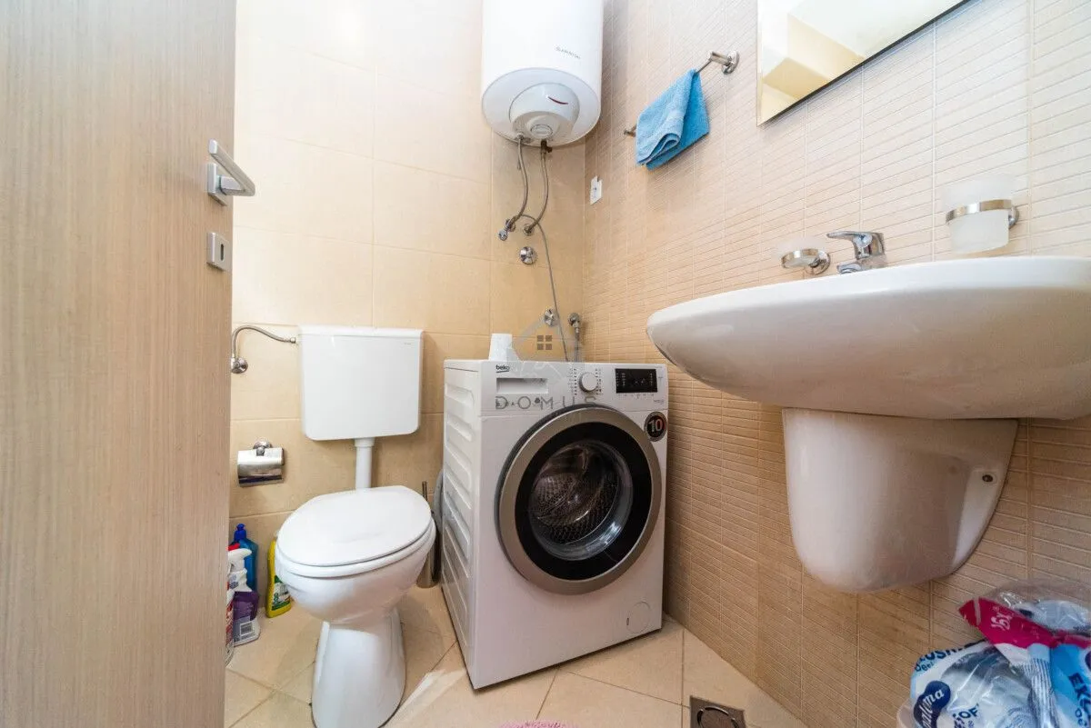 Small bathroom equipped with a washbasin, toilet, washing machine, and water heater.