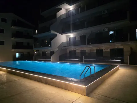 Noćni prikaz stambene zgrade sa osvijetljenim bazenom u dvorištu. - image 19