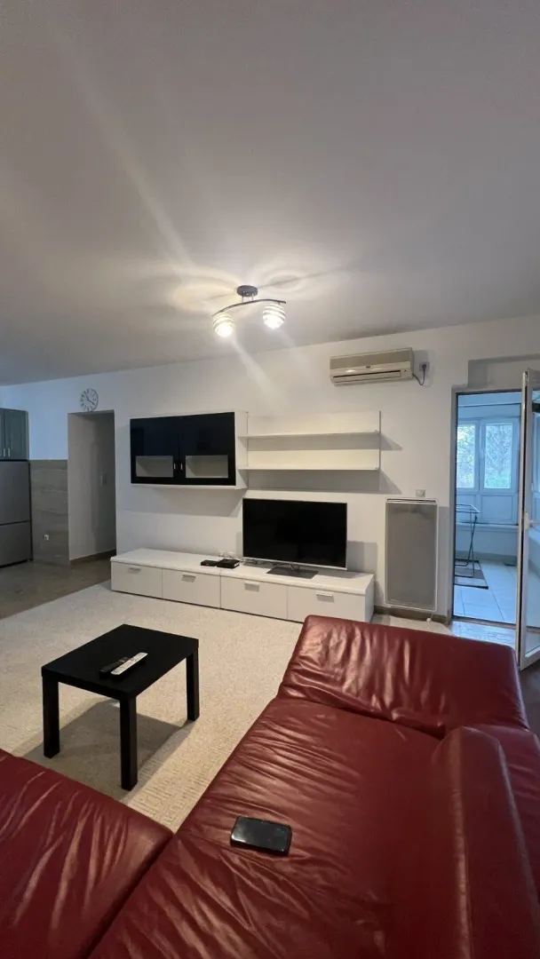 Bright living room with a red leather sofa and a TV cabinet.