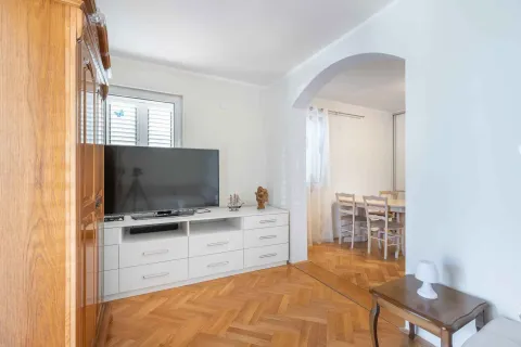 Dnevna soba sa TV komodom i pogledom na trpezariju kroz luk. - image 8