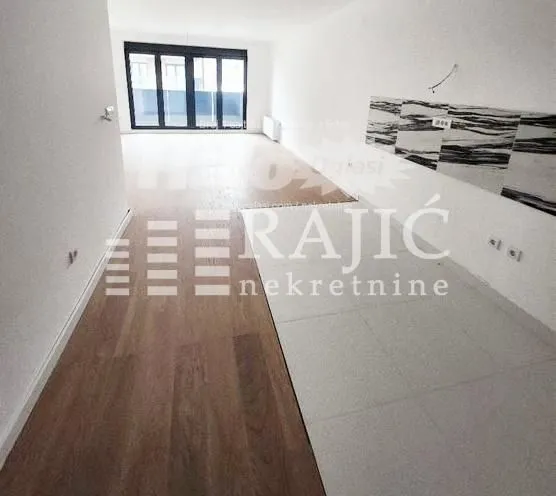 Spacious empty room with combined parquet and tile flooring.