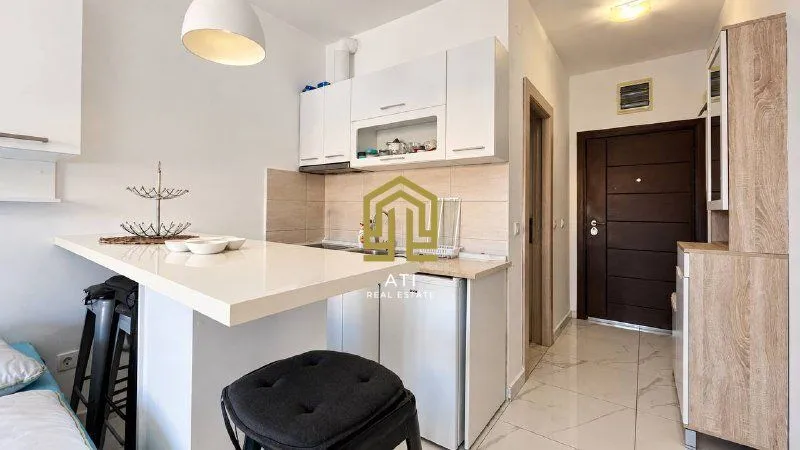 Small white kitchen with a breakfast bar and a bar stool.
